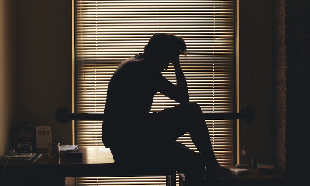 혼자 창가에 앉아 생각에 잠긴 사람의 실루엣